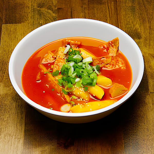 Dagiya's Tteokbokki, a Korean dish with rice cakes and fish cakes in a red sauce, topped with green onions.