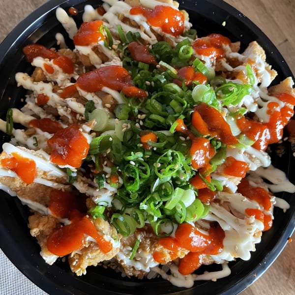 Dagiya's Korean fried chicken topped with white sauce, red chili sauce, green onions, and sesame seeds.
